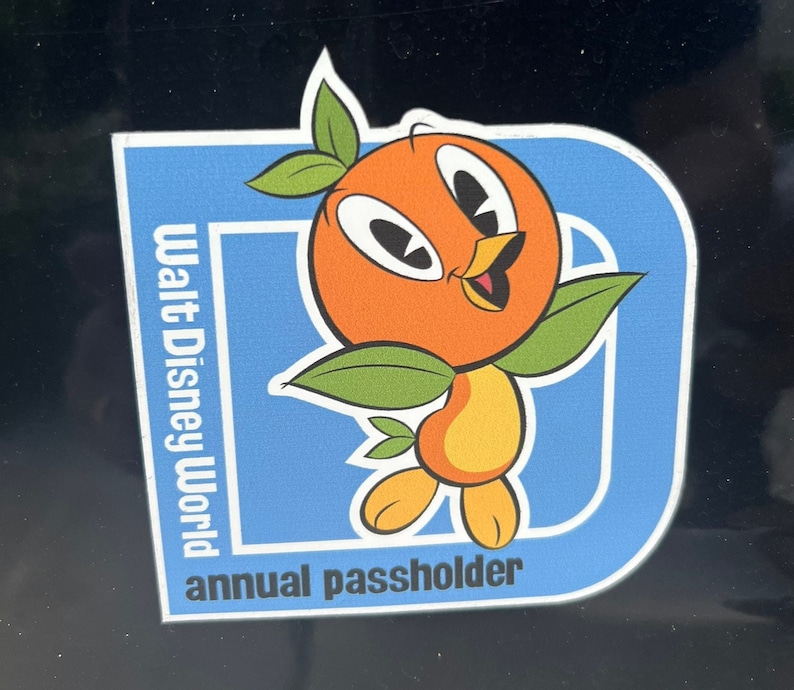 Pu&ograve; includere: Adesivo blu e bianco con un personaggio di uccello arancione e il testo "Walt Disney World annual passholder".