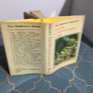 May include: A book titled "Cacti & Other Succulents" from "The Discoverer's Series" with a yellow spine and a colorful illustration of cacti and succulents on the cover.