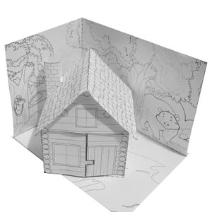 May include: A black and white pop-up card featuring a small house with a chimney and a roof. The house is surrounded by trees and a bear. The card is designed for coloring.