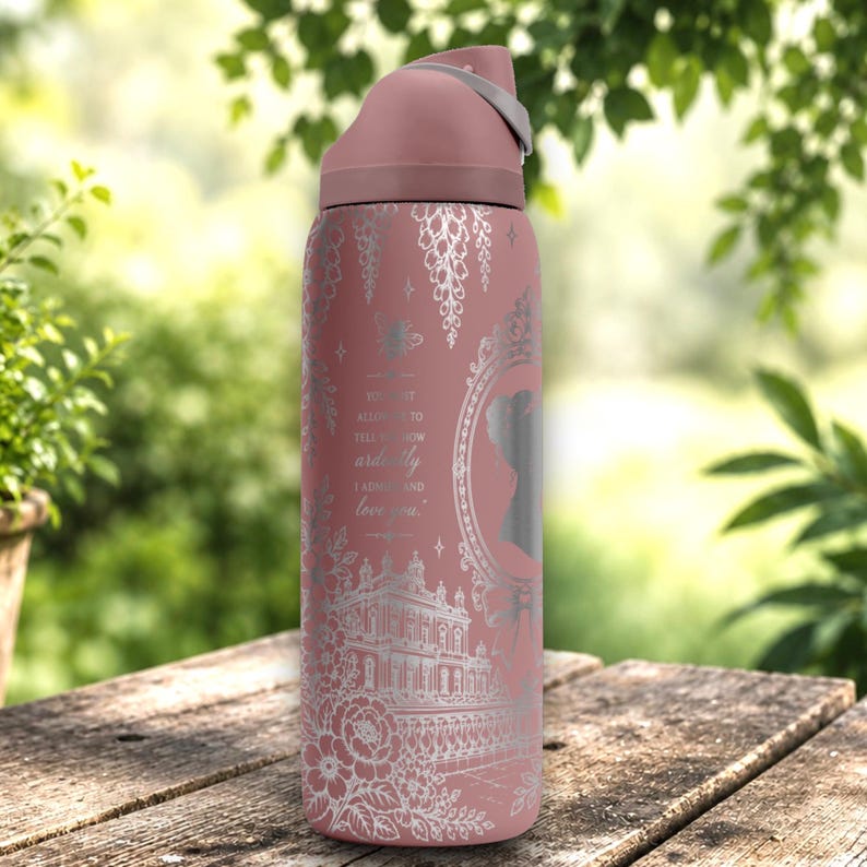 May include: A dusty rose water bottle with a silver-toned etched design featuring a grand estate, floral motifs, and the text: You must allow me to tell you how ardently I admire and love you. The bottle has a matching rose-colored lid with a gray handle.