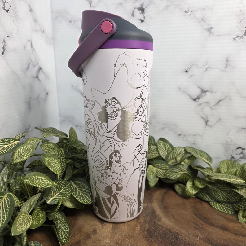 Puede incluir: Una botella de agua aislada blanca con asa y tapa moradas. La botella presenta un dise&ntilde;o plateado de contorno de villanos de dibujos animados. La tapa es gris con un acento morado. La botella mide unos 25 cm de alto.