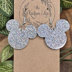 May include: Silver glitter Mickey Mouse earrings with silver hooks. The earrings are on a brown card with the text "the Kustom Edge".