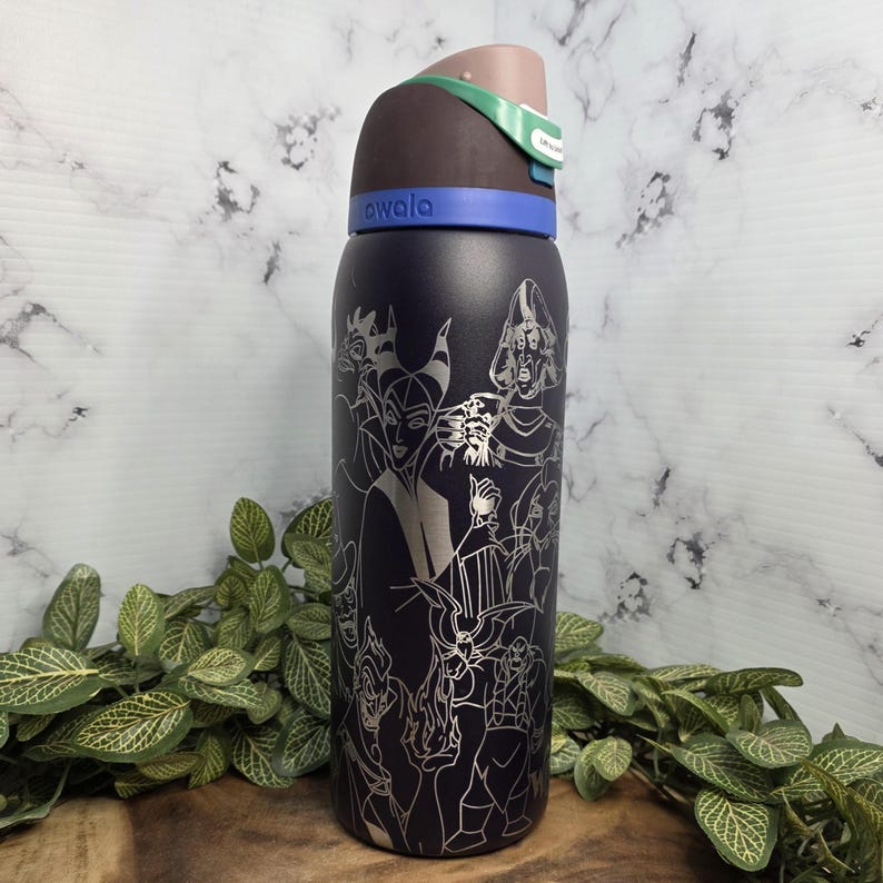 Puede incluir: Una botella de agua aislada azul oscuro con un dise&ntilde;o plateado grabado de villanos de dibujos animados. La botella tiene una tapa marr&oacute;n, verde y azul. La marca "Avala" est&aacute; impresa en la botella.