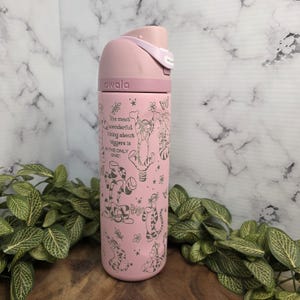 May include: A pink Owala water bottle with a flip-top lid. The bottle features a Tigger design with the quote, "The most wonderful thing about tiggers is I'm the only one!" The bottle has a capacity of 24 ounces.