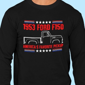 May include: Black long-sleeve t-shirt with a white silhouette of a 1953 Ford F150 pickup truck. The text "1953 Ford F150" is in red and the text "America's Favorite Pickup" is in white. The shirt has red, white, and blue stars and stripes.