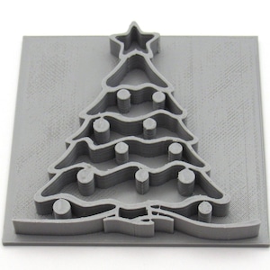 May include: A gray 3D printed Christmas tree ornament with a star on top and a series of circles representing ornaments on the branches.