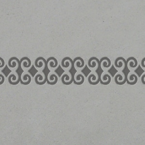 May include: A gray and white patterned border with a repeating design of interlocking swirls.