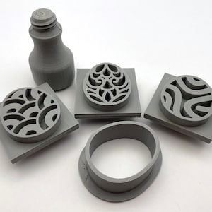 May include: A set of five gray plastic stamps with different geometric designs. The stamps are used for creating patterns on clay or other materials.