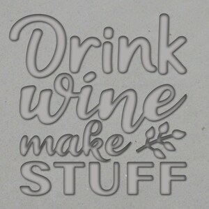 以下が含まれることがあります： グレーの背景に、スタイリッシュなフォントで「Drink wine make stuff」というテキストが書かれています。 「make」の右側に、葉のついた小さなつるがあります。