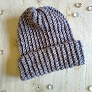 Puede incluir: Un gorro de punto gris con textura de canal&eacute;.