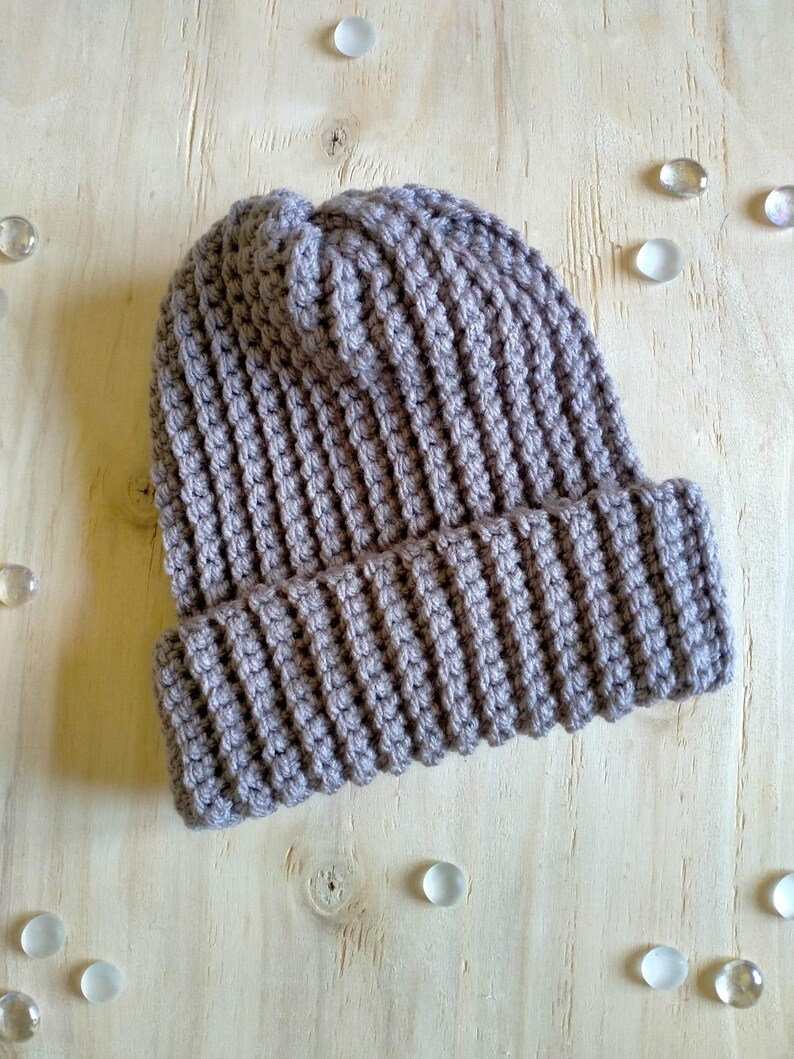 Puede incluir: Un gorro de punto gris con textura de canal&eacute;.