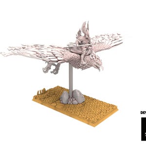 Op de afbeelding: Gedetailleerd miniatuurbeeldje van een gevleugeld wezen met een ruiter, gemonteerd op een voetstuk. De figuur is lichtgekleurd, mogelijk wit of grijs, met ingewikkelde details. De basis is rechthoekig en bruin. De tekst "DESIGNED BY" en een logo zijn zichtbaar.