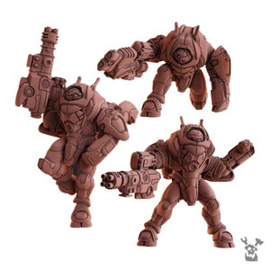 Può includere: Tre robot in miniatura di plastica marrone con diverse armi. I robot sono in piedi su uno sfondo bianco.