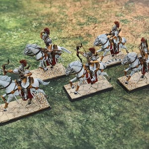 Könnte beinhalten: Sechs weiße Miniaturpferde mit Reitern in silberner Rüstung und roten Umhängen. Die Reiter halten Bögen und Pfeile. Die Pferde stehen auf Sockeln mit einer steinartigen Textur.