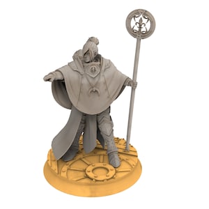 May include: A grey plastic miniature figurine of a female figure wearing a long robe and holding a staff with a circular top. The figure is standing on a round, gold-coloured base.