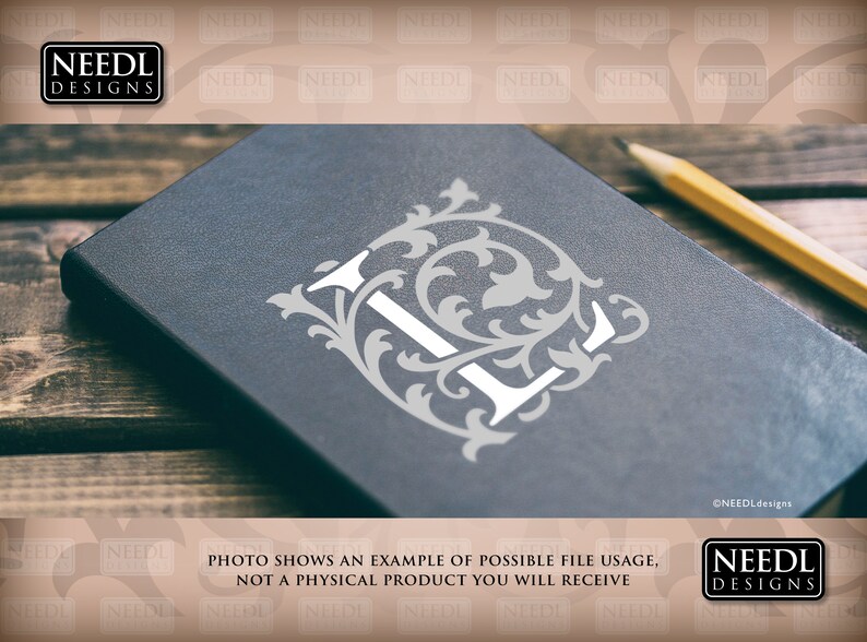 May include: A close-up of a black notebook with a white letter L surrounded by a decorative floral design. The notebook is on a wooden surface with a pencil lying next to it.