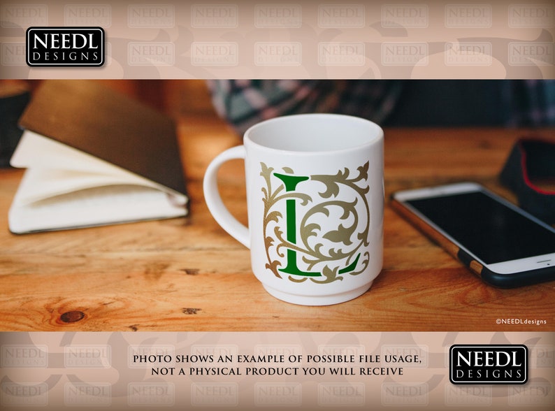 May include: A white ceramic mug with a green and gold letter L design. The mug is sitting on a wooden table with a notebook and a cell phone.