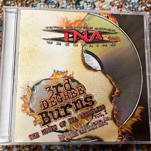 Puede incluir: Una caja de CD con el logotipo de Total Nonstop Action (TNA) Wrestling. La portada del álbum tiene un diseño desgastado con el título "3rd Degree Burns" y el texto "The Music of TNA Wrestling Vol. I". El CD está en una caja de plástico transparente.