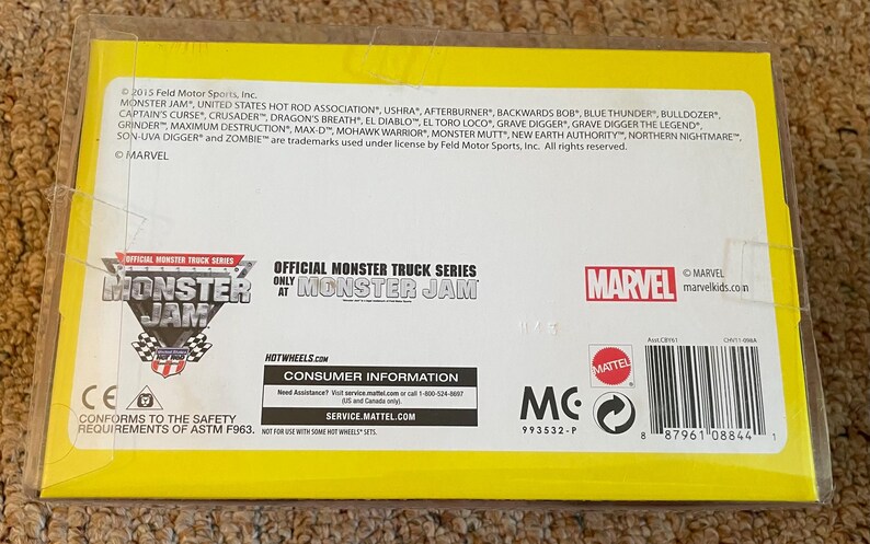 May include: A yellow and white Monster Jam toy package. The package features the Monster Jam logo, the Marvel logo, and the names of various monster trucks. The package also includes consumer information and a barcode.