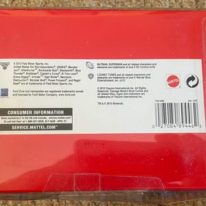 May include: A red box with a clear plastic cover. The box contains text from Feld Motor Sports, Looney Tunes, and Mattel. The box also has a barcode and the text "CONSUMER INFORMATION" and "SERVICE.MATTEL.COM".