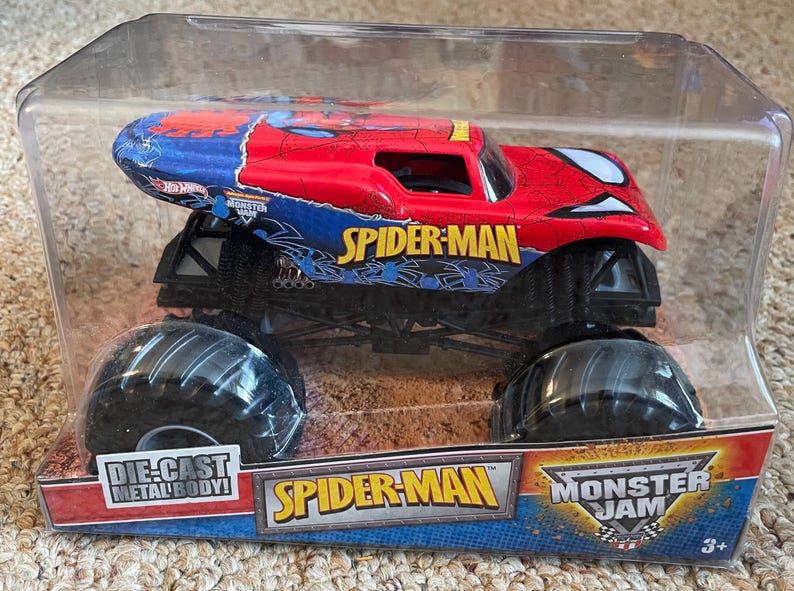 May include: A Spider-Man Monster Jam die-cast metal body truck toy. The truck is red and blue with the Spider-Man logo and graphics. The toy is in a clear plastic package.