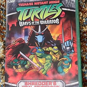 Könnte beinhalten: Teenage Mutant Ninja Turtles DVD. Das Cover zeigt die Turtles mit Shredder und den Text "Ways of the Warrior" und "Shredder's Final Countdown". Die DVD-Hülle ist grün.