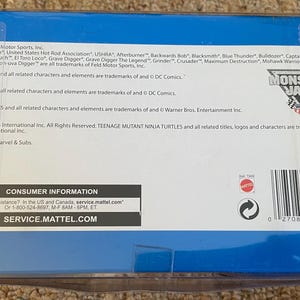 May include: A blue box with the Monster Jam logo and text. The box contains information about trademarks and consumer information. The box has a barcode and the text "SERVICE.MATTEL.COM".