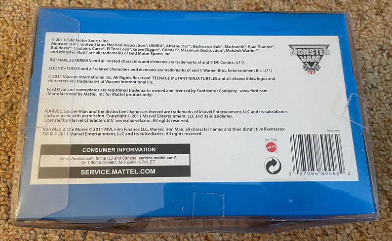 May include: A blue box with a white label featuring text about Monster Jam, DC Comics, and Marvel characters. The box includes a barcode and the Monster Jam logo.