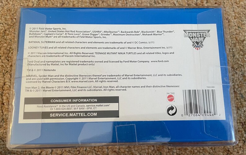 May include: A blue plastic package with text and logos for Monster Jam, including trademarks for various characters and companies. The package includes a barcode and consumer information.