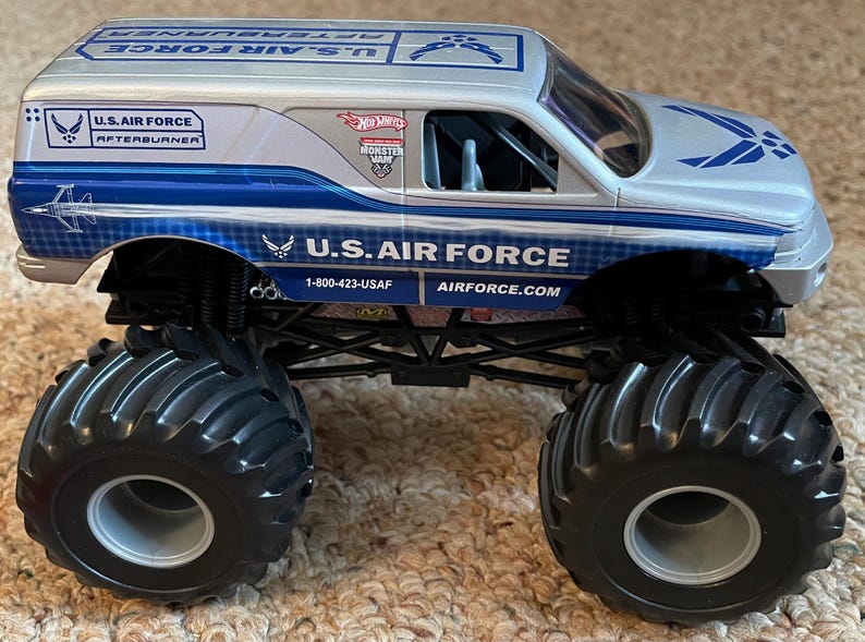 Pu&ograve; includere: Un camion mostro giocattolo della U.S. Air Force argento e blu con grandi pneumatici neri. Il camion presenta la scritta "U.S. AIR FORCE" e "AFTERBURNER". Il logo Hot Wheels &egrave; visibile.