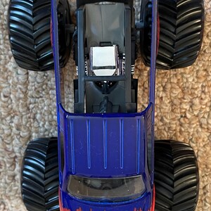 Może przedstawiać: Niebiesko-ż&oacute;łta zabawka monster truck z dużymi czarnymi oponami. Na przodzie ciężar&oacute;wki widnieje napis "PURE ADRENALINE". Widok ciężar&oacute;wki z g&oacute;ry.