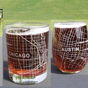 May include: Four clear drinking glasses filled with a brown liquid, likely beer, each etched with a city map design. The cities labeled are Richmond, Chicago, Austin, and Walla Walla. The glasses vary in shape and size.