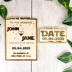 Puede incluir: Una tarjeta de madera para guardar la fecha con un tema de Star Wars. La tarjeta es de color marrón claro con letras doradas. El texto dice "Save the Date" y "05.04.2025" con los nombres "John Jane" debajo de la fecha.
