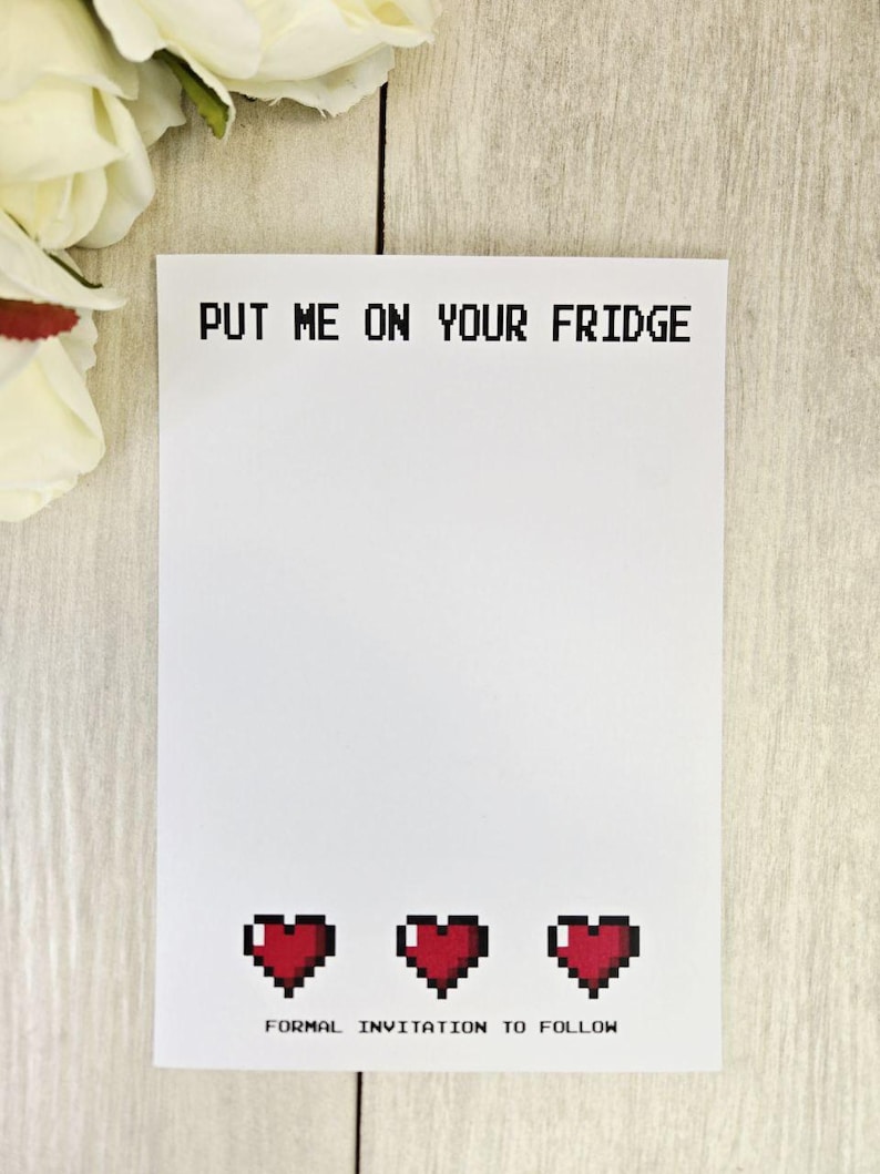 Op de afbeelding: Witte uitnodigingskaart met de tekst "PUT ME ON YOUR FRIDGE" in pixellettertype. Onderin staan drie gepixelde rode harten, met daaronder de tekst "FORMAL INVITATION TO FOLLOW". Witte bloemen op de achtergrond.