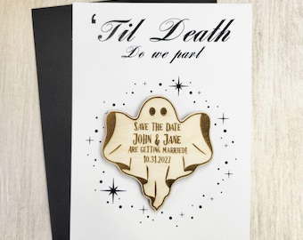 May include: A save-the-date card with a wooden ghost-shaped magnet. The card reads "'Til Death Do we part" and "Save the Date John & Jane are getting married! 10.31.2027." The card is black and white with star accents.
