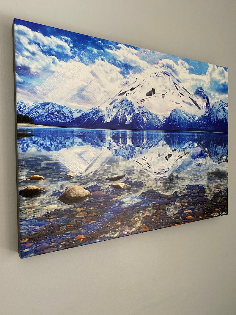May include: A canvas print of a snowy mountain range reflected in a still lake. The water is clear and blue, with small rocks visible at the bottom. The sky is a bright blue with white clouds. The mountains are covered in snow and ice. The print is signed "T. Haas Butler" in the lower right corner.
