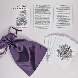 May include: A set of white oracle cards with black ink illustrations and text. The cards are in a purple satin bag. The cards include the title "Intuitive Oracle Cards" and the text "How to Use the Intuitive Oracle Cards" and "Invocation".