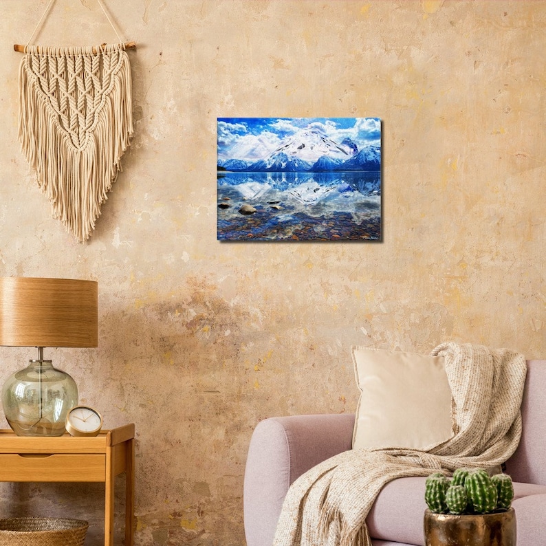 May include: A scenic photograph of a mountain range reflected in a still lake. The mountains are snow-capped and the sky is a bright blue with white clouds. The water is a deep blue and the reflection of the mountains is clear.