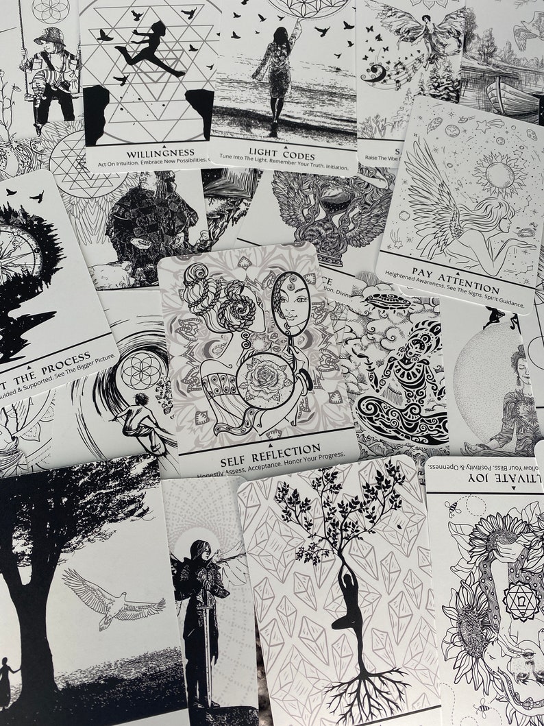 May include: A set of black and white oracle cards with various illustrations and text. The cards feature themes of self-reflection, light codes, willingness, and paying attention. The cards are laid out on a white surface.