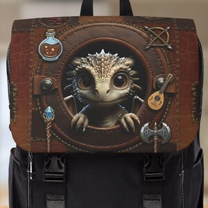 Puede incluir: Mochila negra con solapa marrón con aspecto de cuero. La solapa presenta un diseño circular con un dragón de dibujos animados, una botella de poción, un bastón, un laúd y un hacha. La mochila tiene correas y hebillas negras.