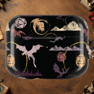 May include: Black AirPod case with a fantasy-themed design. The case features dragons, dice, mountains, and clouds in shades of purple, gold, and white. The design is set against a black background.