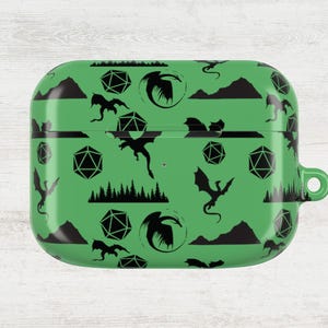 May include: Green AirPod case with a black dragon and dice pattern. The case features a repeating design of dragons, dice, mountains, and trees. The case has a smooth, glossy finish and a small loop for attaching to a keychain.