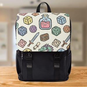 Può includere: Uno zaino nero con una patta color crema con un motivo colorato di dadi, spade, pozioni e un drago. Lo zaino ha una maniglia superiore, spallacci regolabili e due fibbie nere.