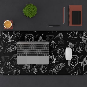 May include: A black desk mat with a white geometric pattern. The mat features a laptop, a mouse, and a coffee cup.