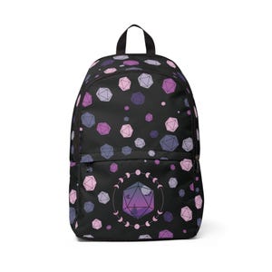May include: A black backpack featuring a repeating pattern of multi-faceted polyhedral dice in shades of pink, purple, and lavender. The front pocket displays a large central twenty-sided die graphic surrounded by a circular lunar phase motif.