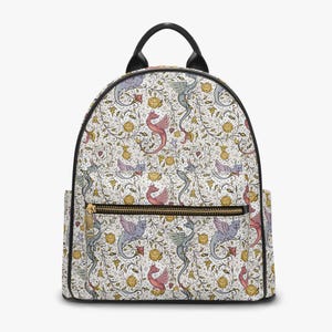 Puede incluir: Una mochila blanca con un patrón repetido de dragones rosas, azules y grises, con detalles florales amarillos. La mochila tiene un asa y ribete negros, una cremallera dorada y dos bolsillos laterales.