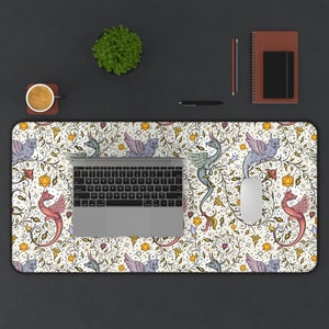 May include: A white desk mat with a repeating pattern of dragons and vines. The dragons are in shades of blue, pink, and green. The vines are in shades of yellow and green. There are also small dice scattered throughout the pattern.