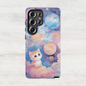 May include: A phone case with a watercolor design of a cat in a galaxy with planets and stars. The cat is white with orange and brown markings and is sitting on a cloud.