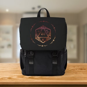 May include: Black backpack with a large, red and orange 20-sided die graphic on the front. The die is surrounded by a circle of smaller dots.