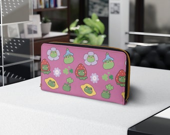 May include: A pink zippered wallet with a repeating pattern of green frogs, strawberries, lemons, flowers, and four-leaf clovers.